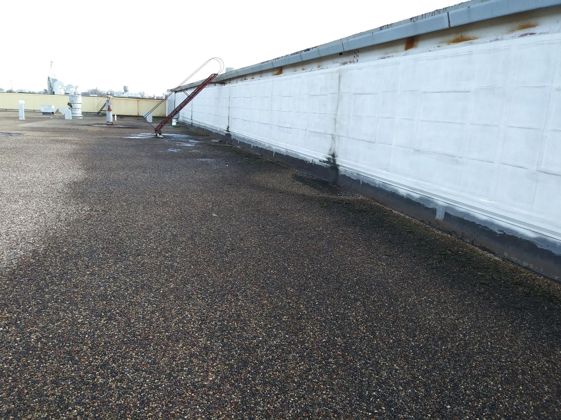 A roof with a white wall and a drain on it