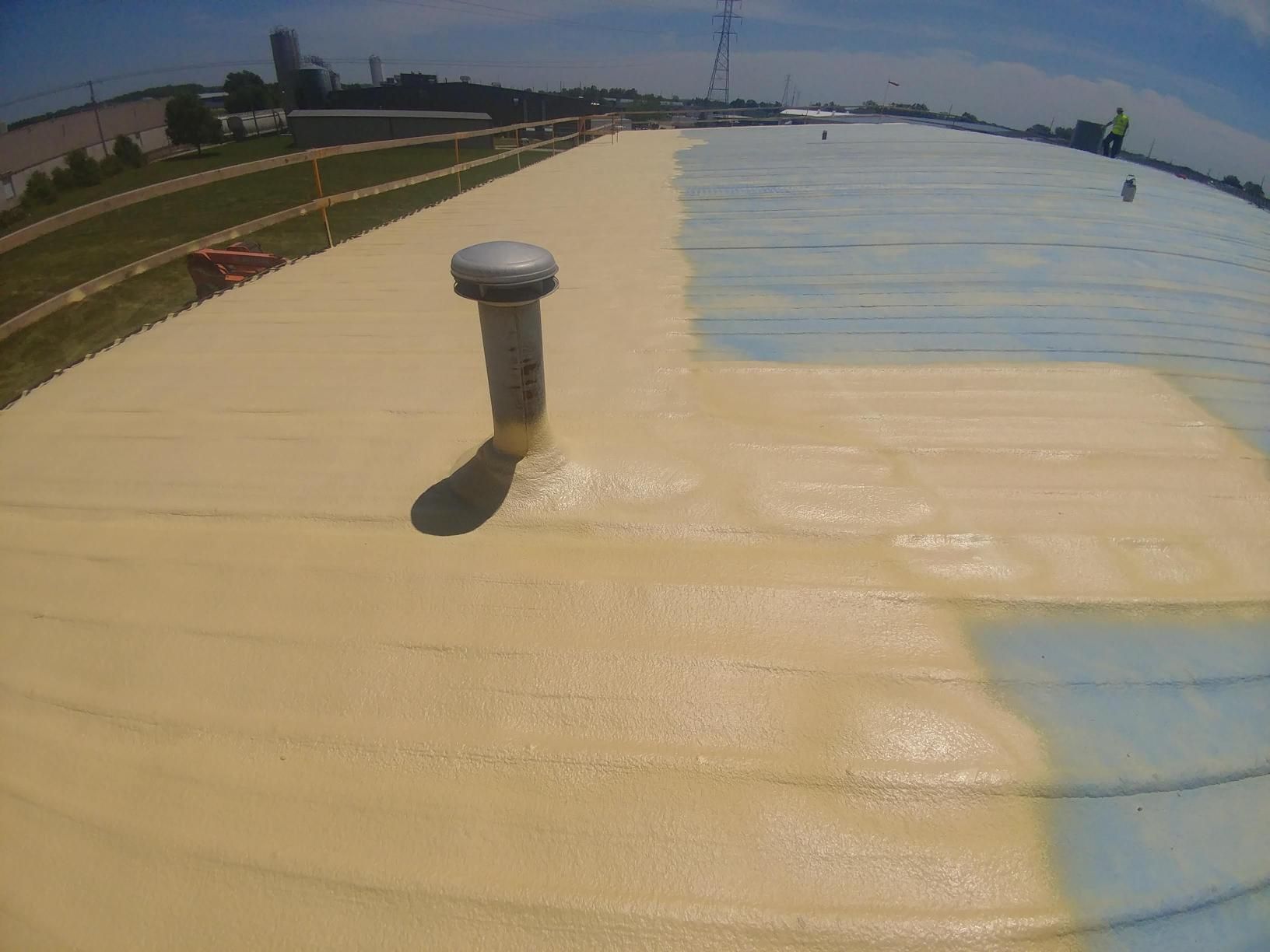 A roof is being sprayed with a yellow and blue foam.