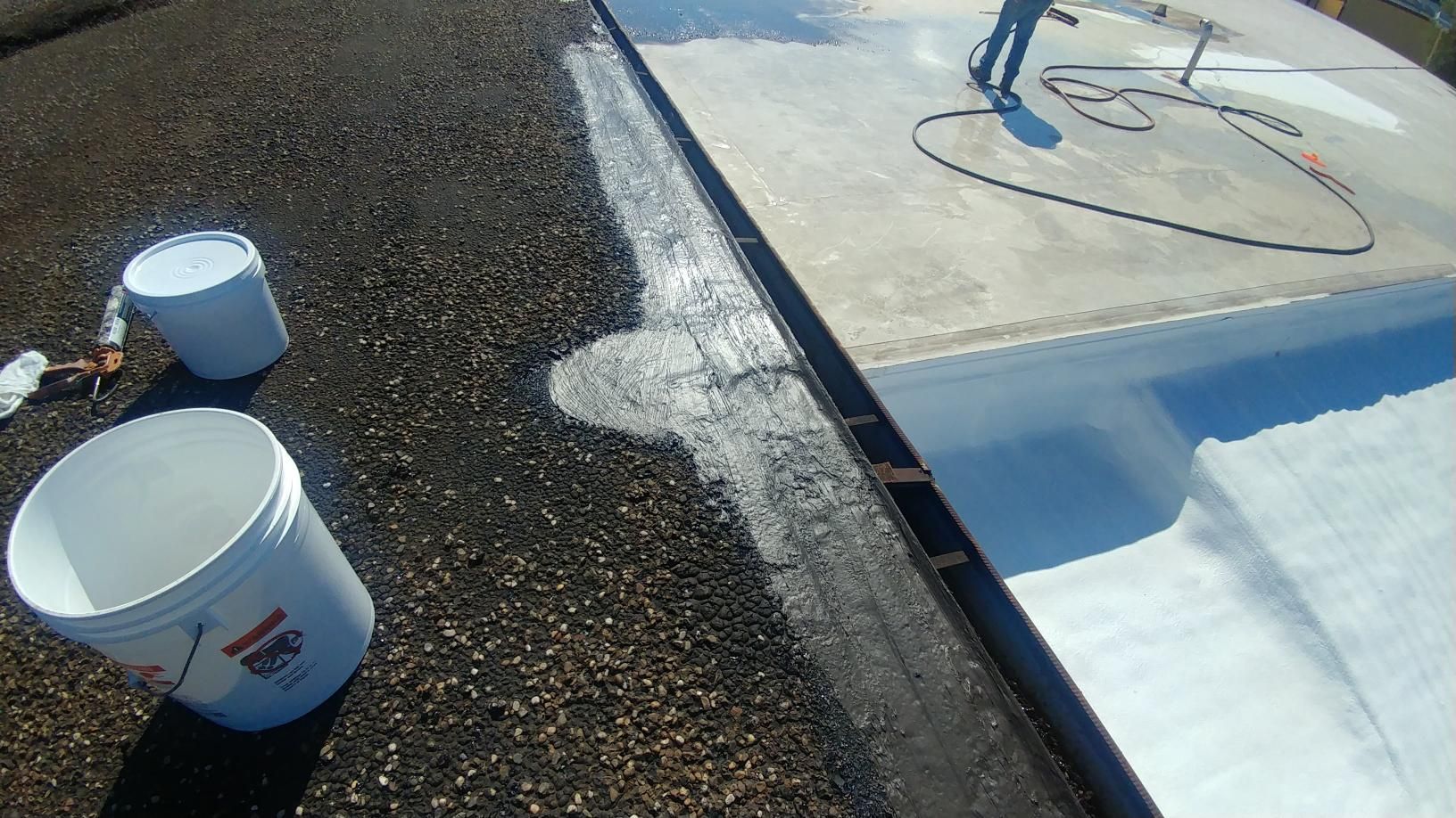A person is painting a roof with white paint