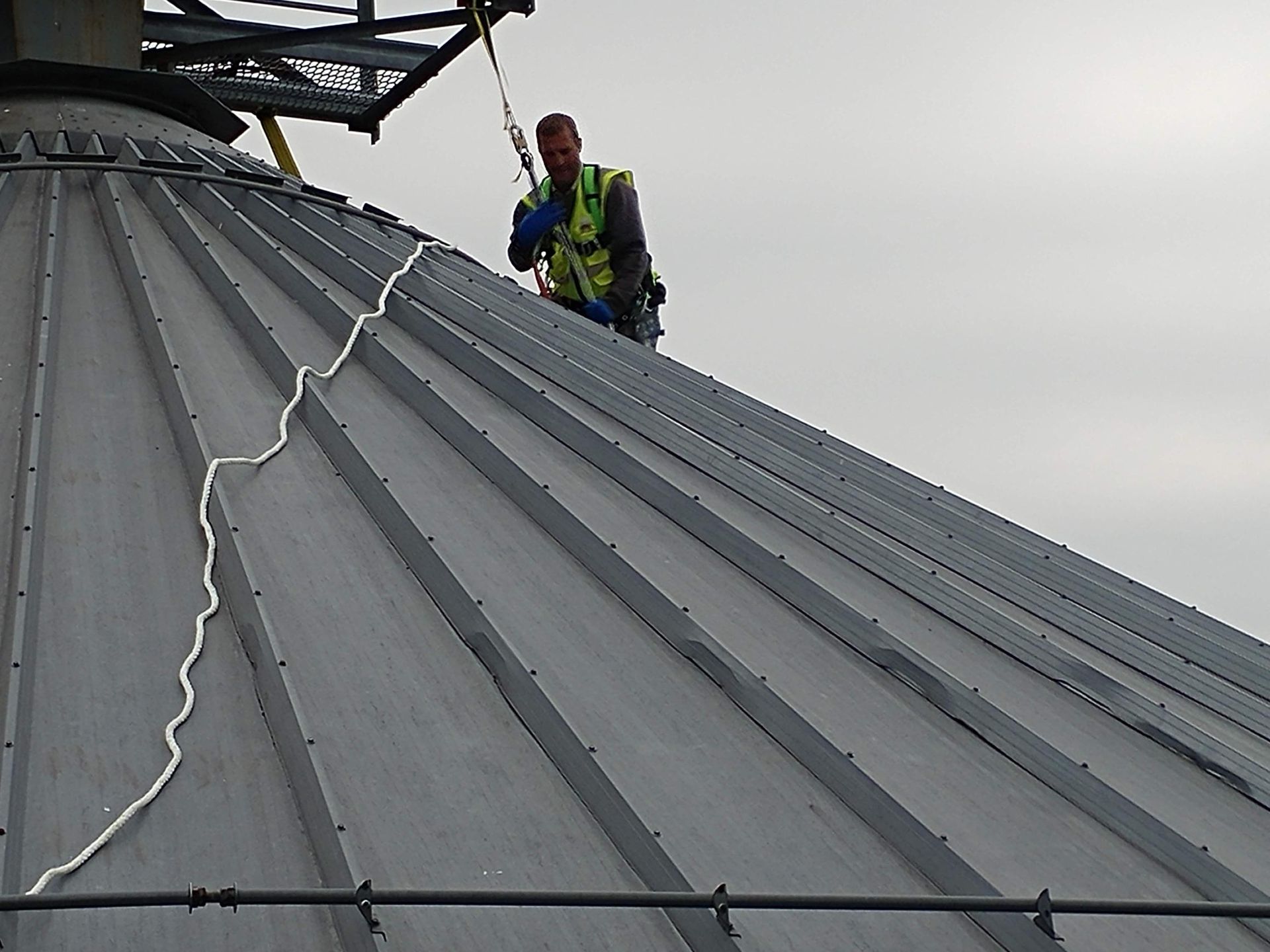 A man is standing on top of a metal roof
