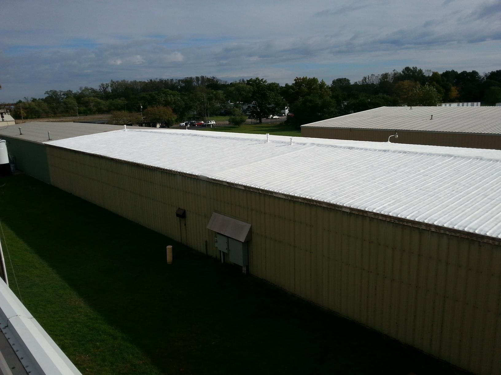 A large building with a white roof is surrounded by grass