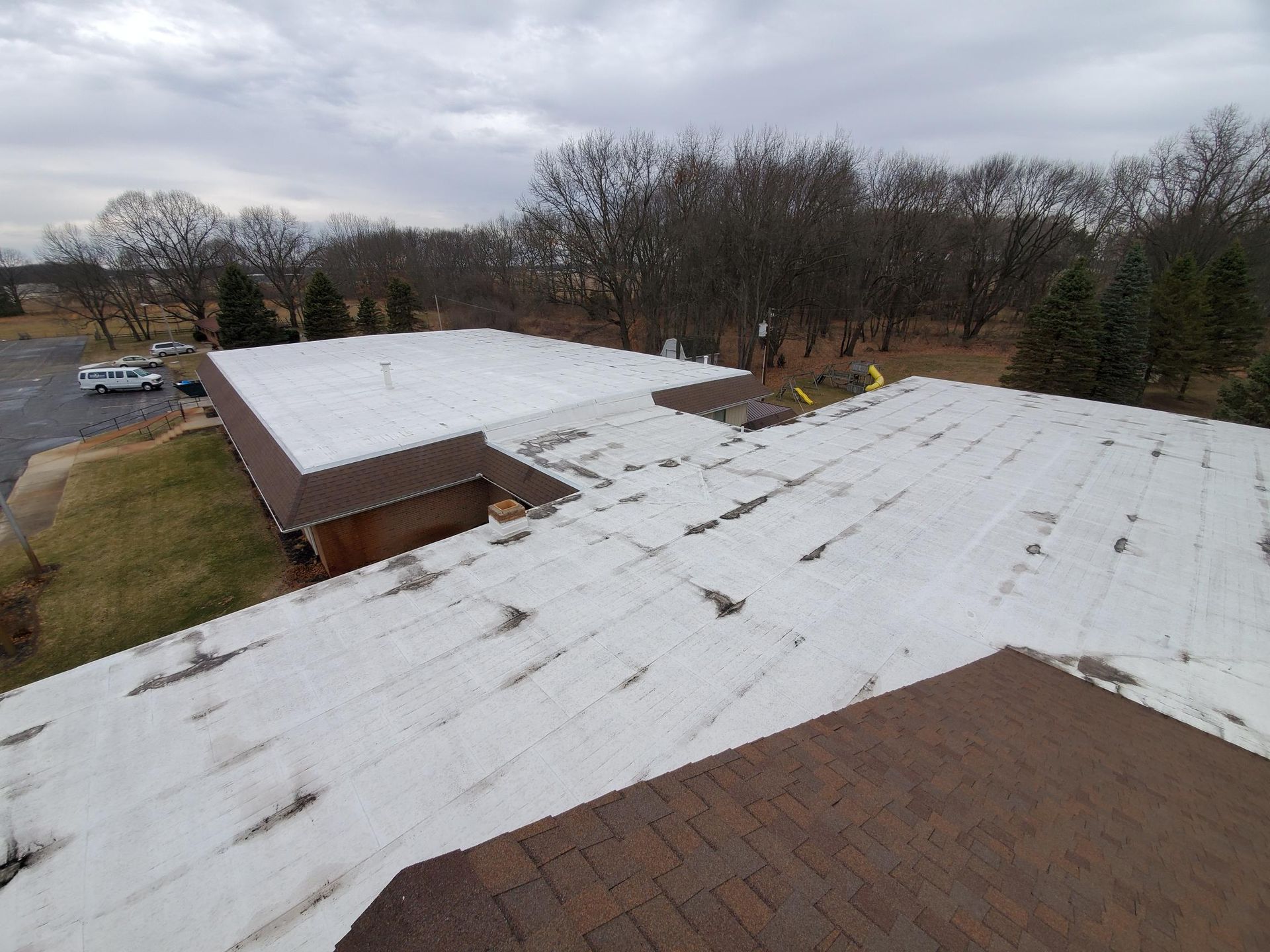 An aerial view of a roof with a white roof and a brown roof.