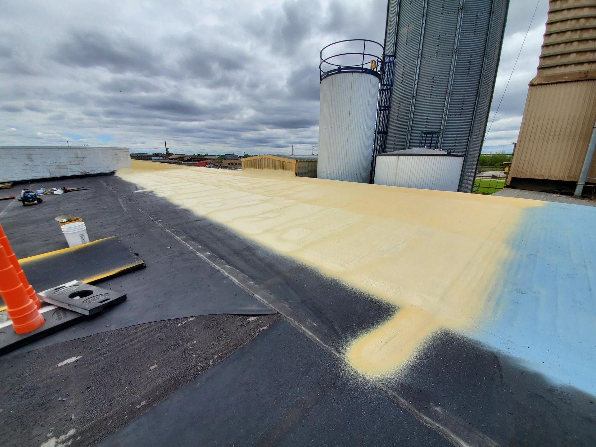 The roof of a building is being painted yellow and blue.