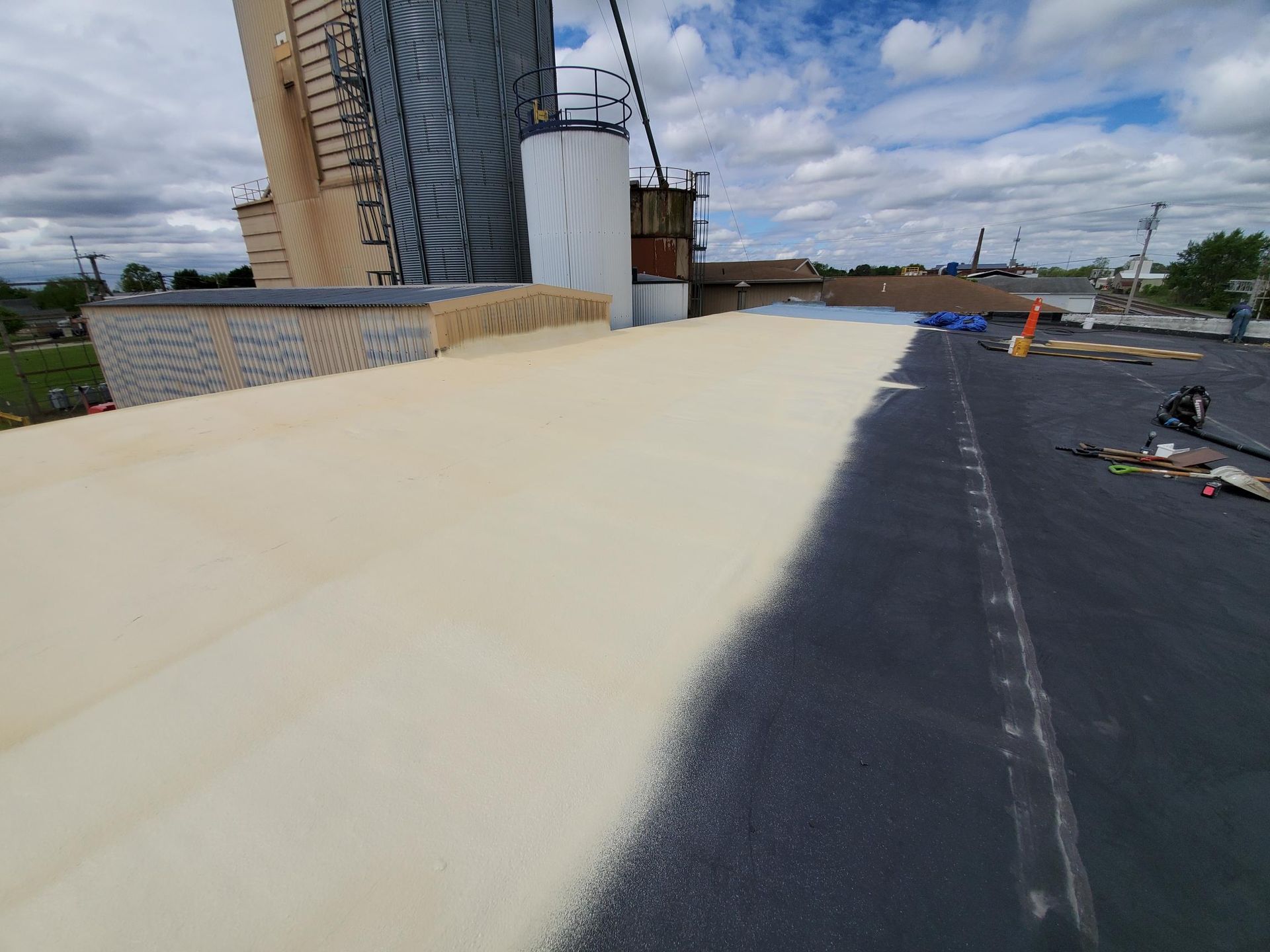 A roof with a lot of foam on it and a silo in the background.