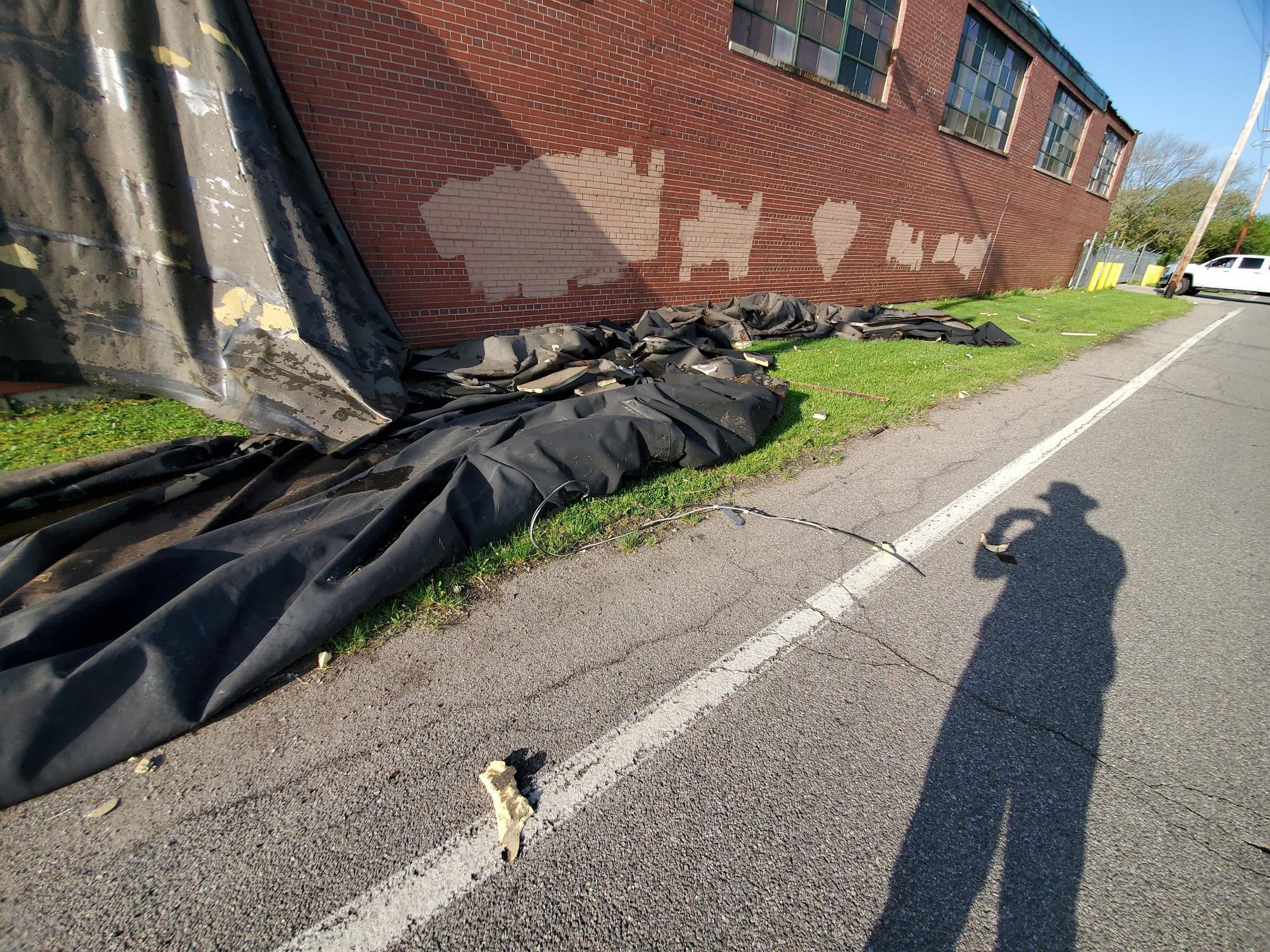 A large tarp is laying on the side of the road next to a brick building.