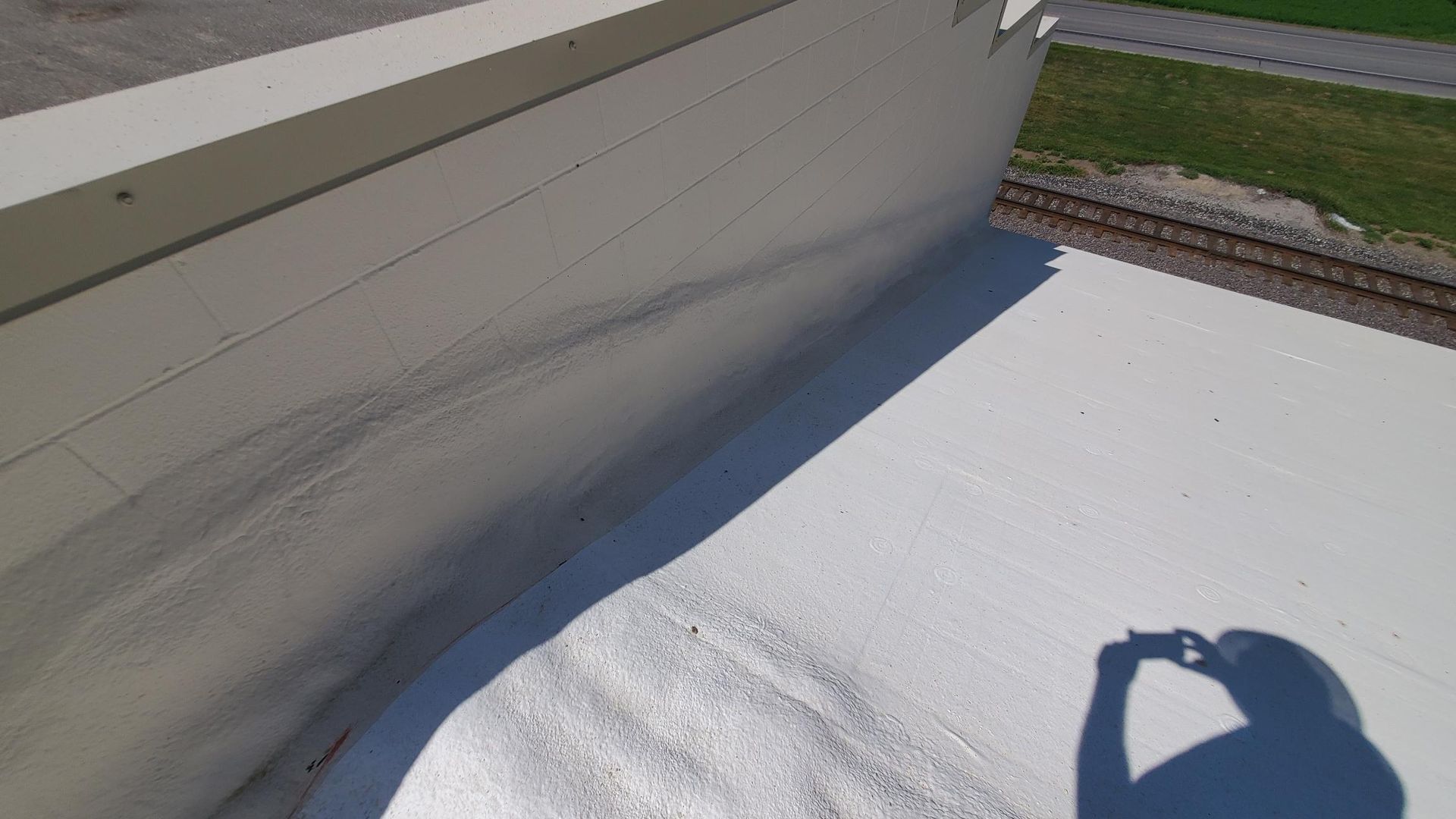 A person is taking a picture of their shadow on a white roof.