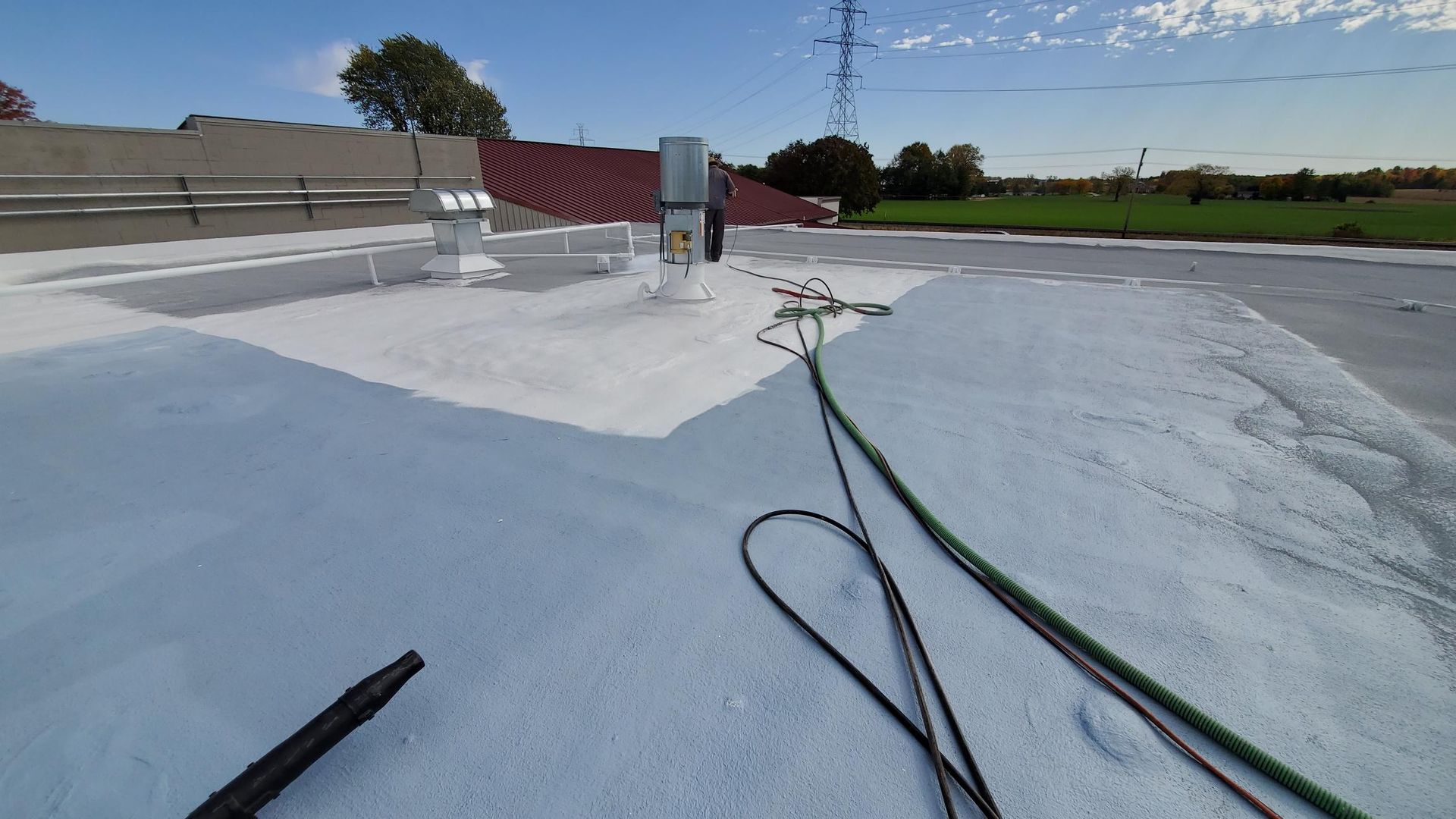 A person is spraying a roof with a hose.