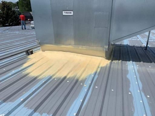 A man is standing on top of a metal roof.
