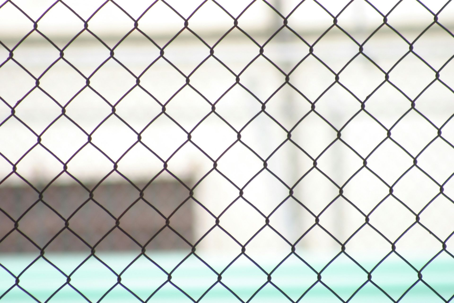 A close up of a chain link fence with a building in the background.