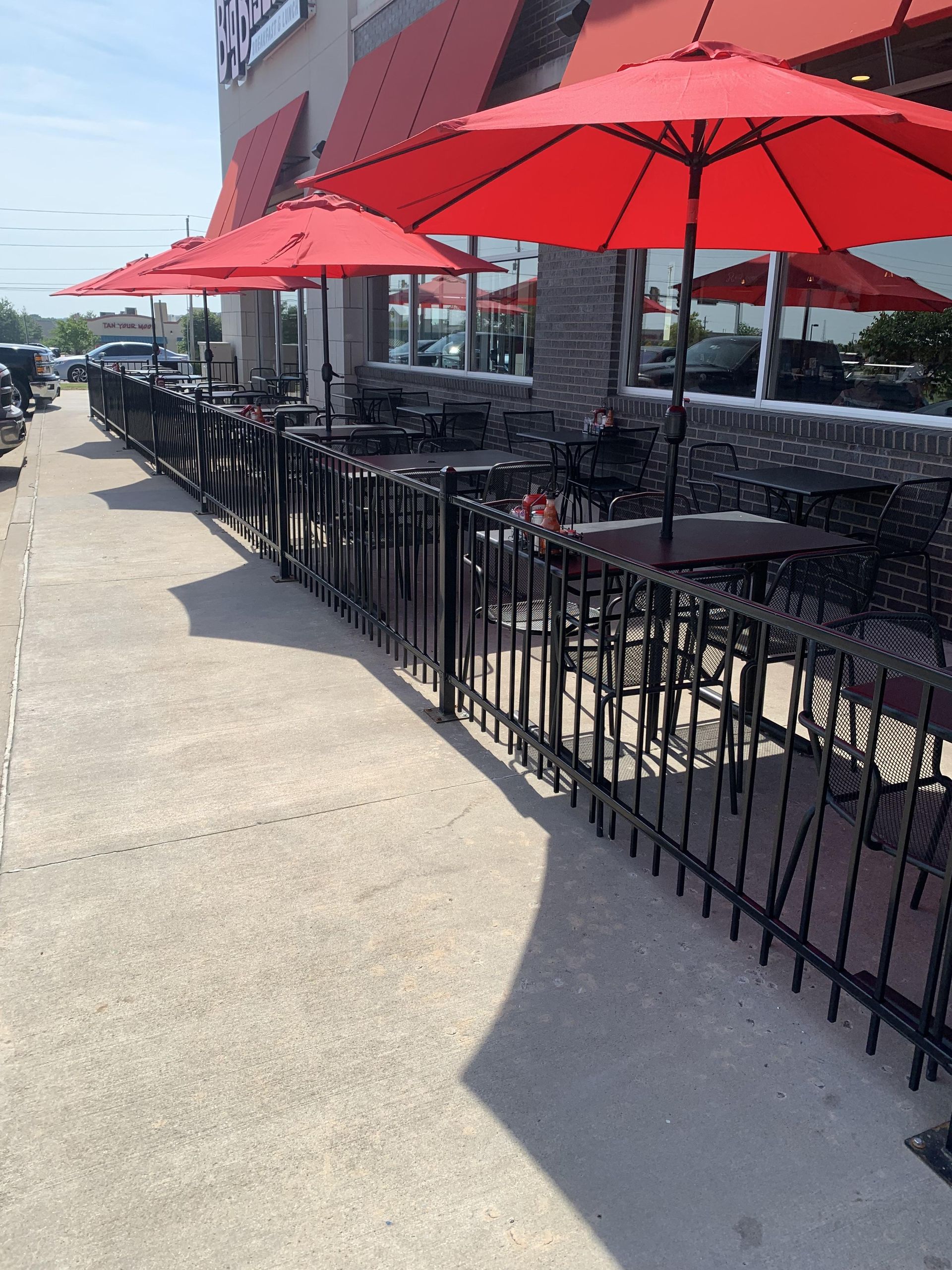 A restaurant patio with red umbrellas and tables