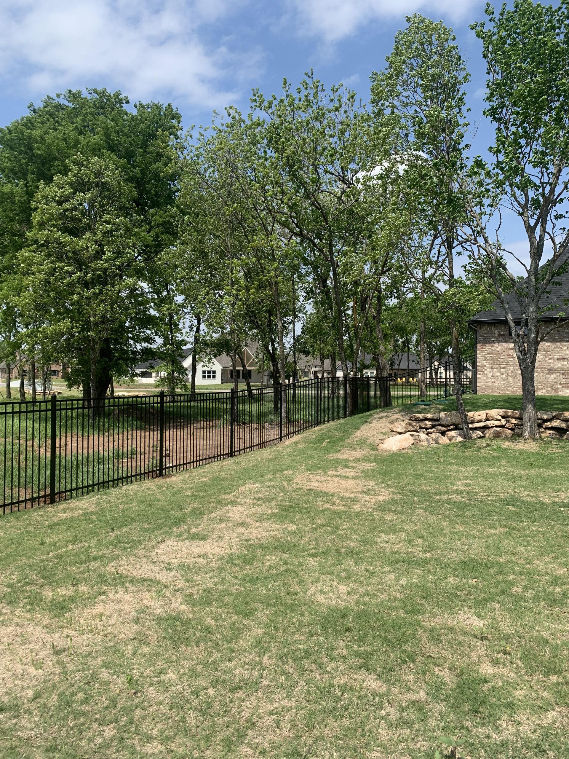 A fence surrounds a grassy field with trees in the background.
