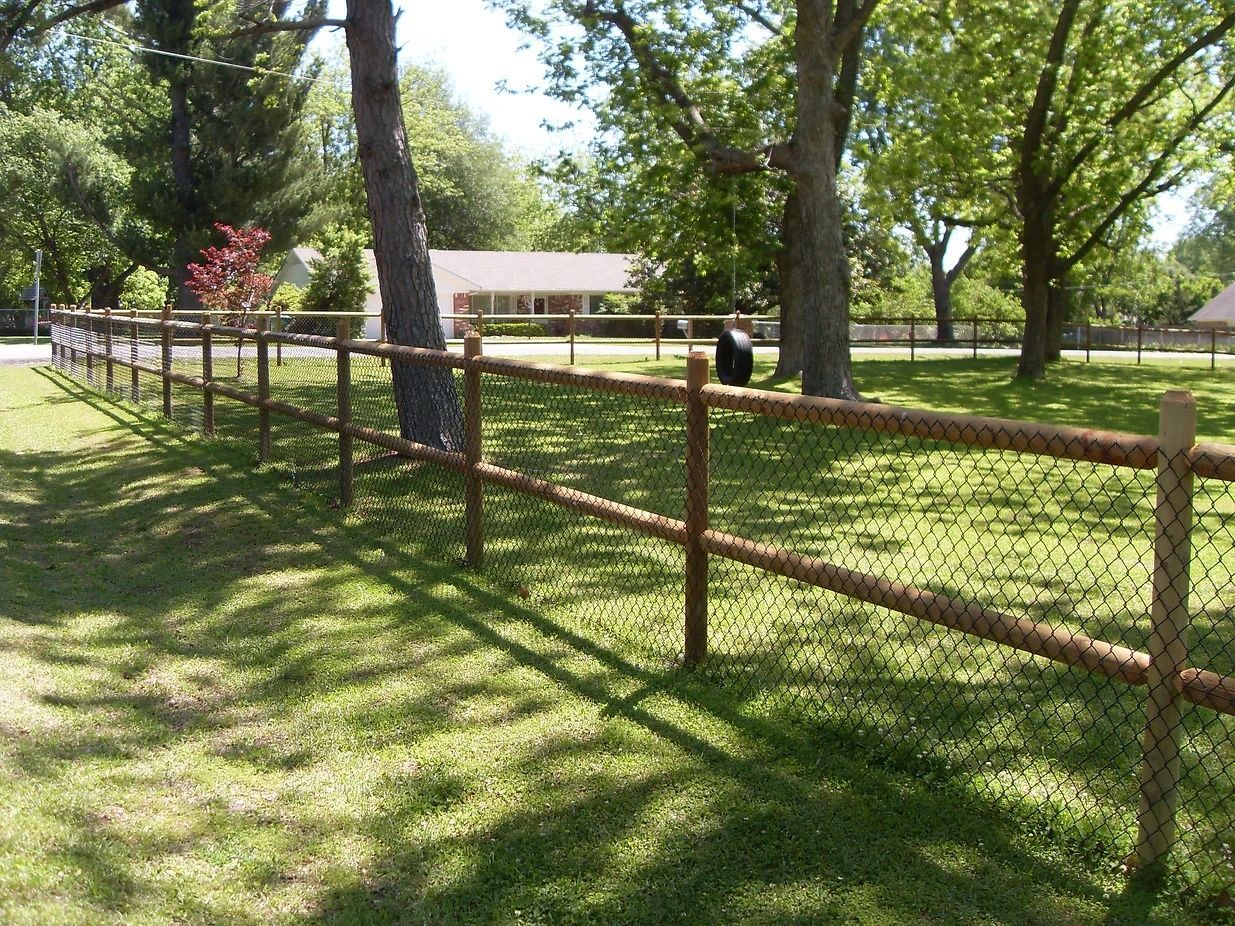 A wooden fence surrounds a lush green field