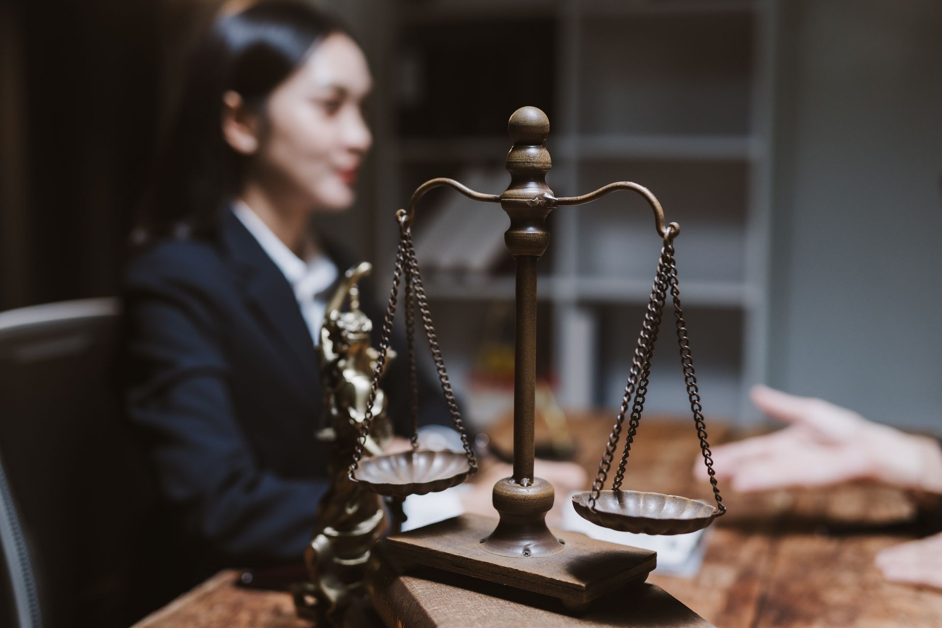 A professional criminal lawyer consulting with a client, featuring a vintage brass scale of justice.