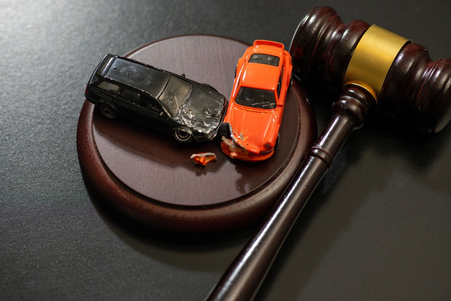 Two toy cars colliding next to a judge's gavel.