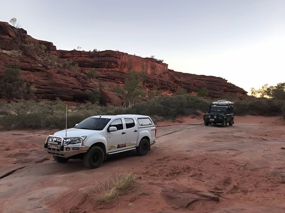 A White Truck Is Parked In A Dirt Field Next To A Black Truck — AHT Towing in Ciccone, NT