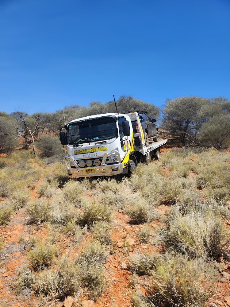 A Tow Truck Is Driving Down A Dirt Road In The Desert — AHT Towing in Ciccone, NT