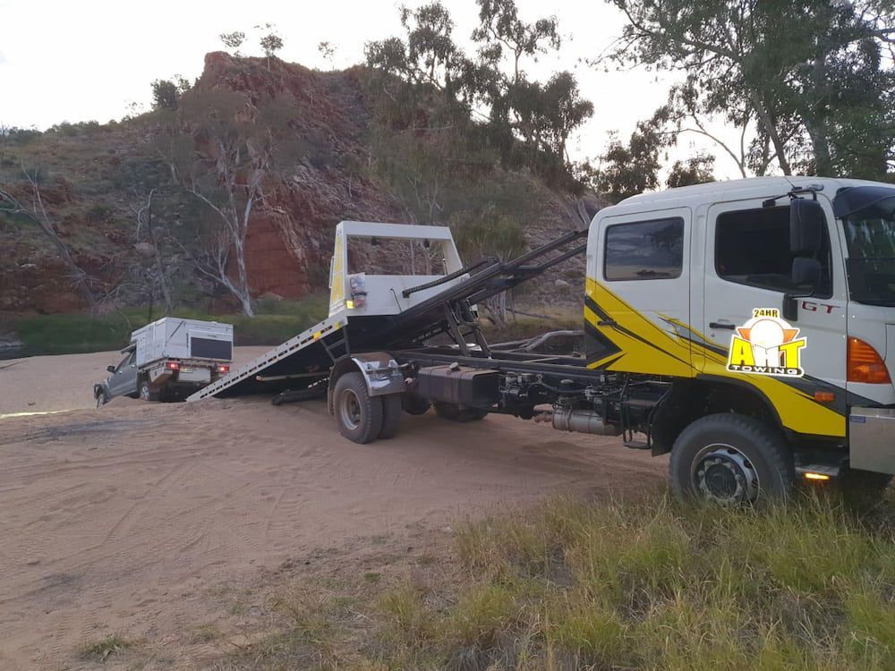 A Tow Truck With A Car On The Back Of It — AHT Towing in Ciccone, NT