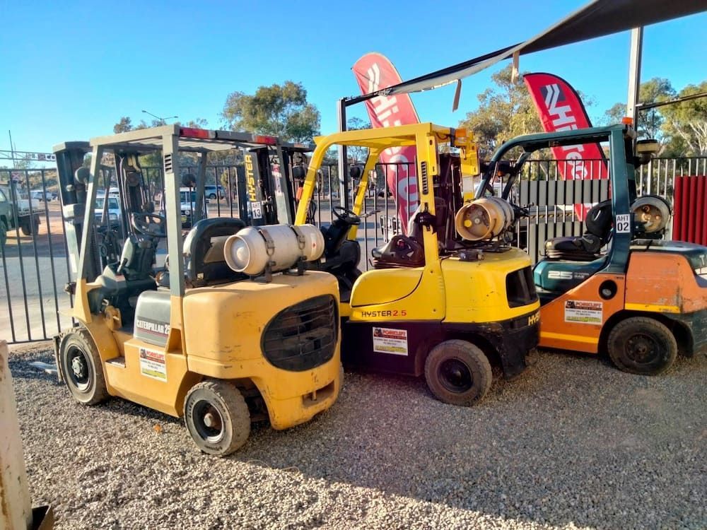 Three Forklifts Are Parked Next To Each Other In A Gravel Lot — AHT Towing in Ciccone, NT