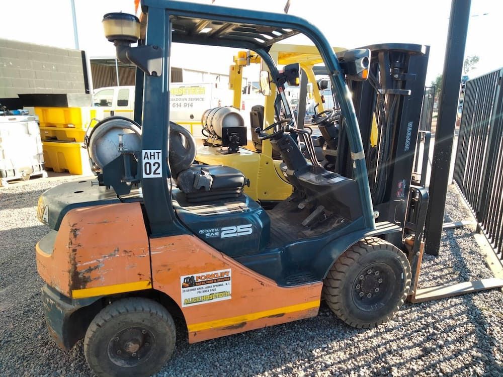 A Forklift Is Parked In A Gravel Lot Next To A Fence — AHT Towing in Ciccone, NT