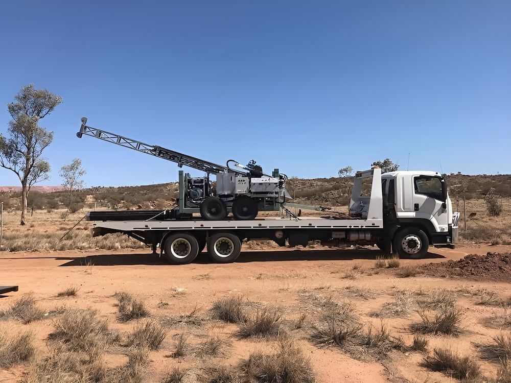 A White Truck With A Crane On The Back Is Parked On A Dirt Road — AHT Towing in Ciccone, NT