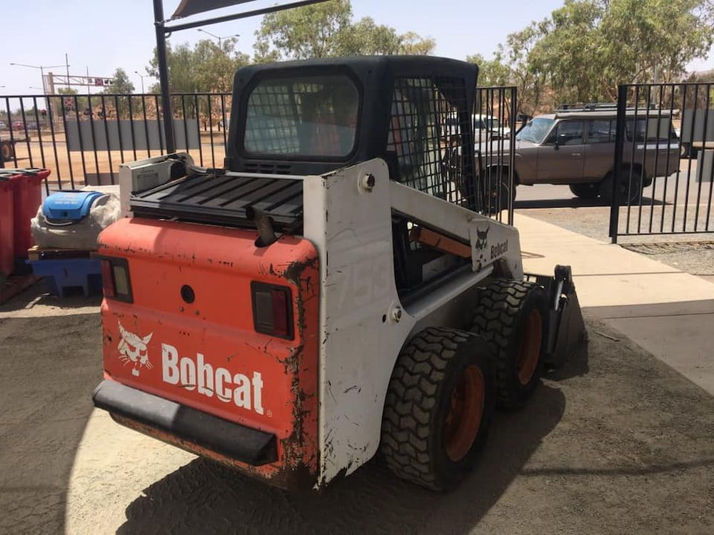 A Bobcat Skid Steer Is Parked In A Parking Lot — AHT Towing in Ciccone, NT