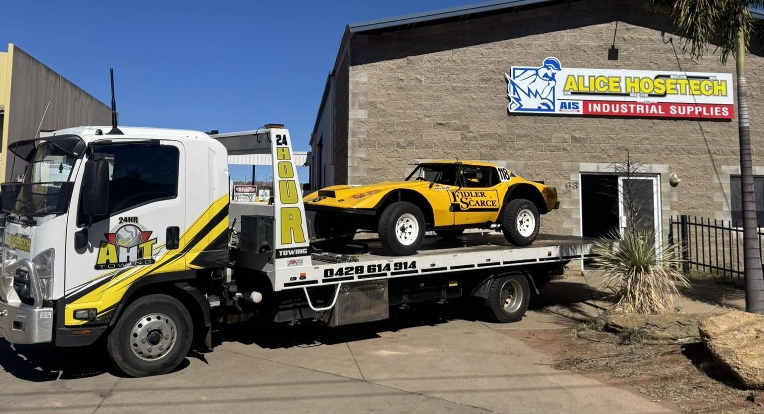 A Yellow Off-road Buggy Is Transported on a Tilt Tray Truck Outside a Building.