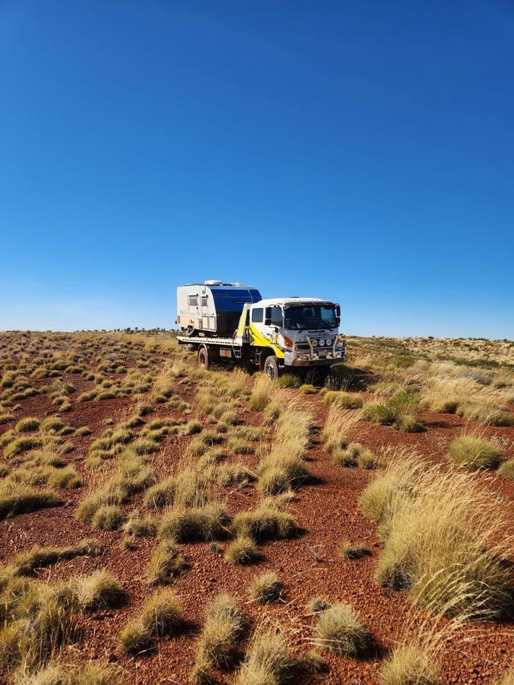Tow truck transporting a caravan across a remote outback landscape