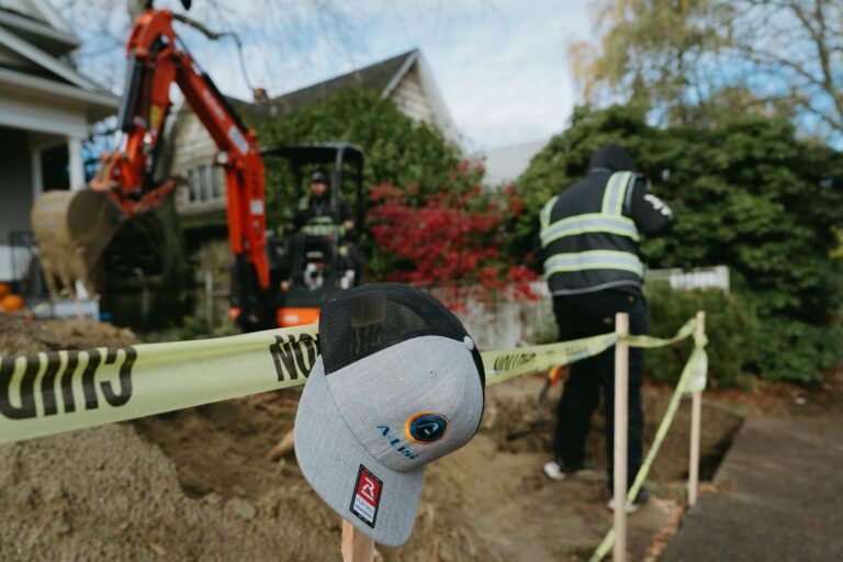 A hat is hanging from a pole in front of a construction site working on a sewer.