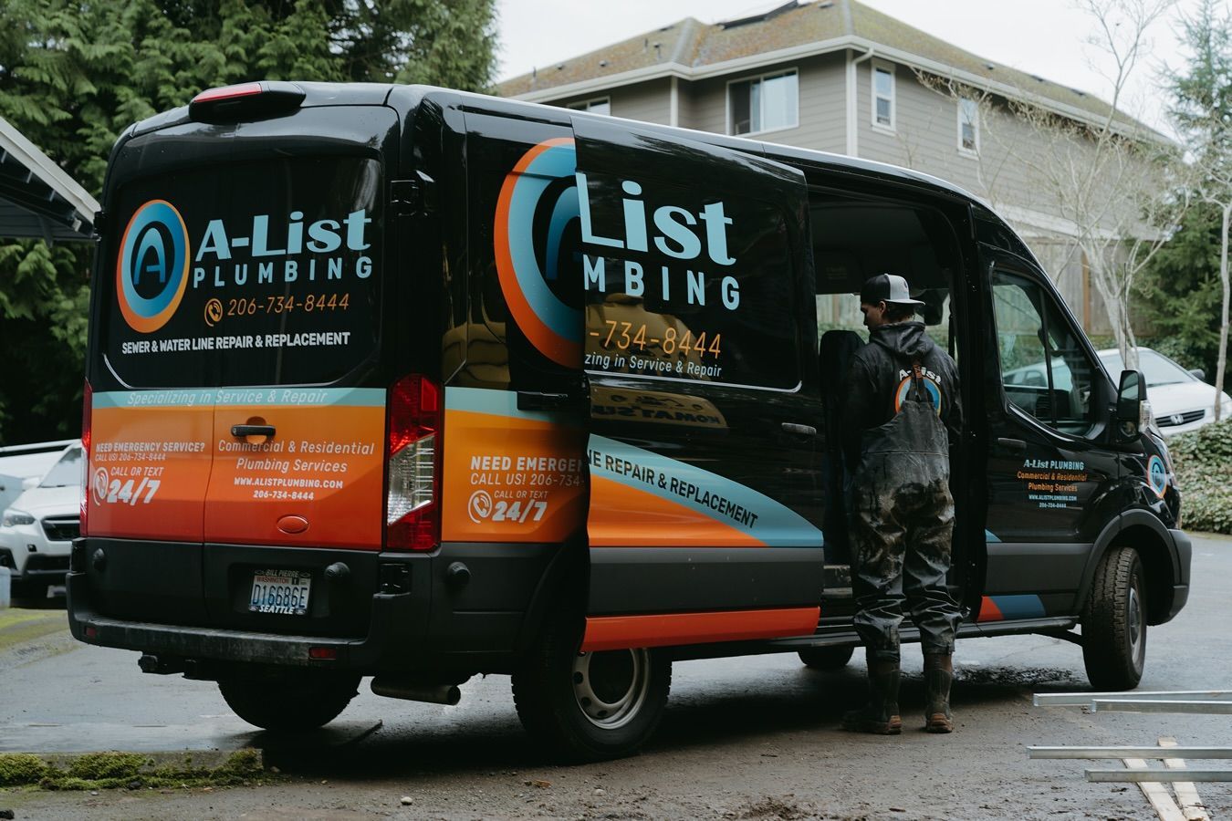 A man is standing next to a van that says a-list plumbing.