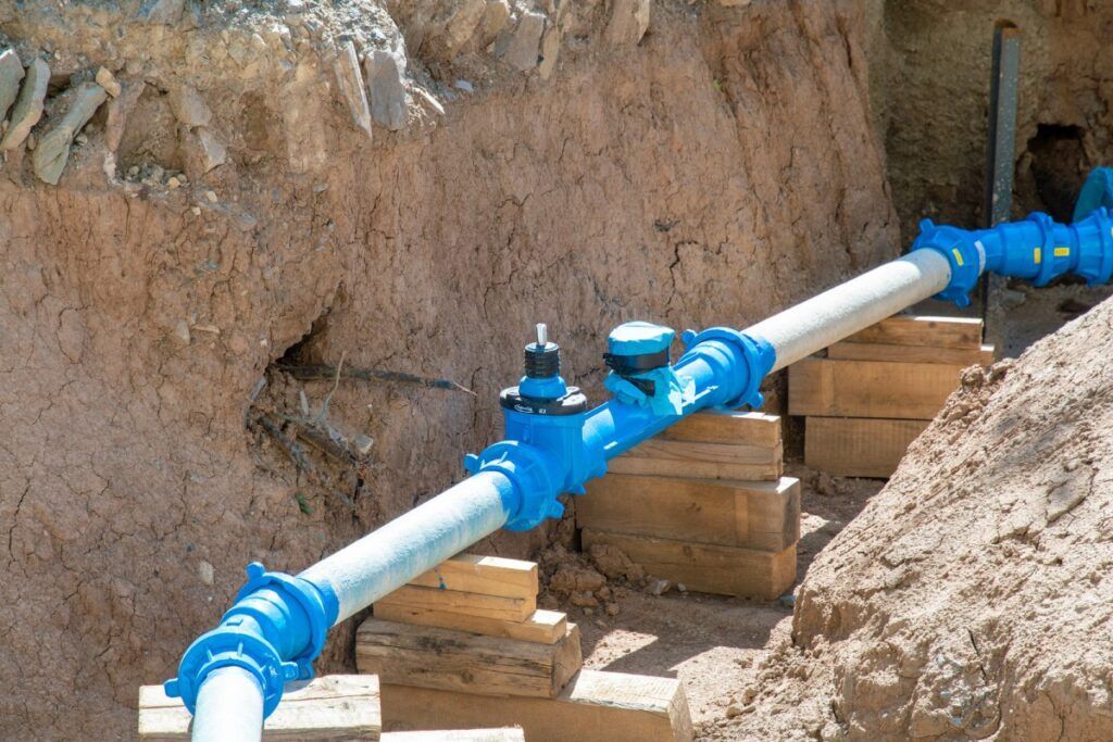 A man wearing green gloves is working on an a-list pipe