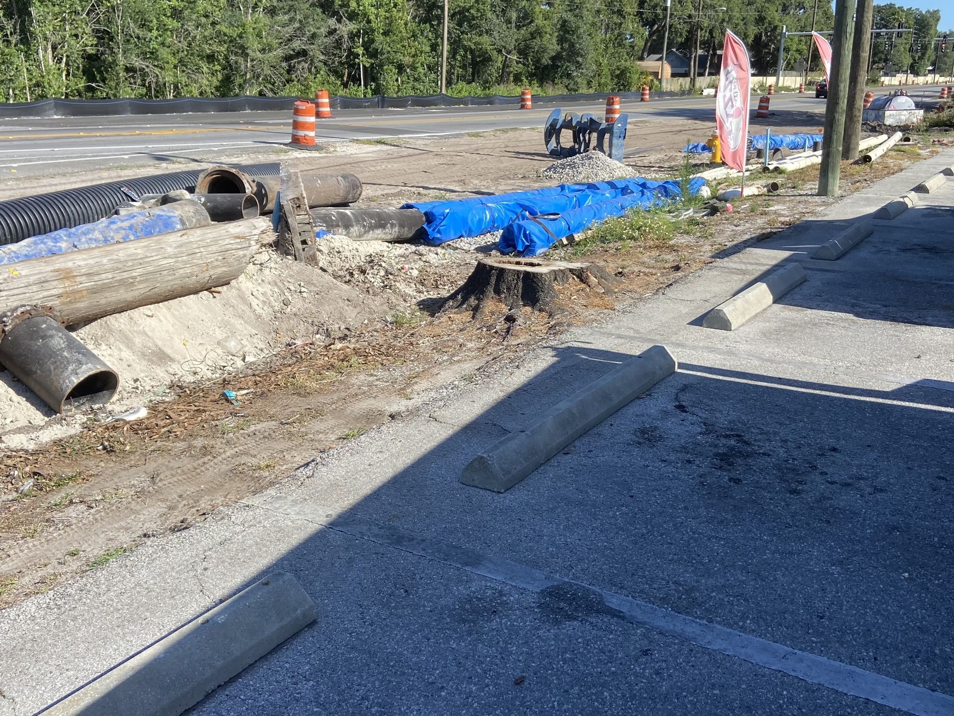 A construction site with a lot of pipes and cones on the side of the road.