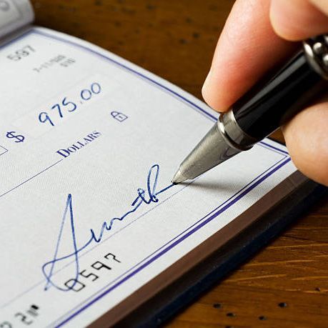 A person is signing a check for 975.00 dollars