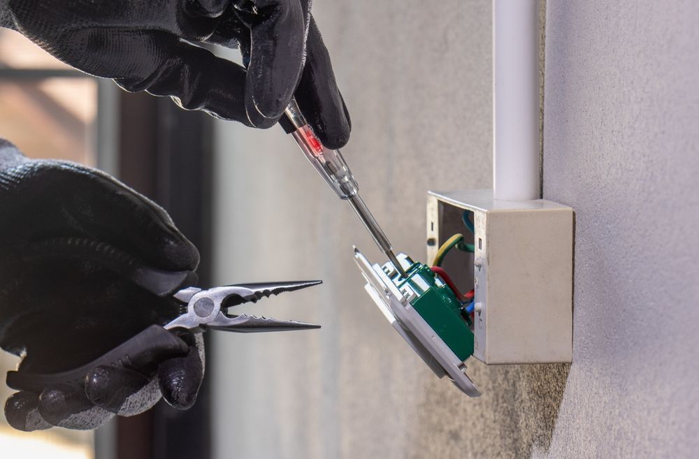 Person With Black Gloves Using Tools to Work on an Electrical Outlet — Mazlin Electrical Services Pty Ltd in Kirwan, QLD