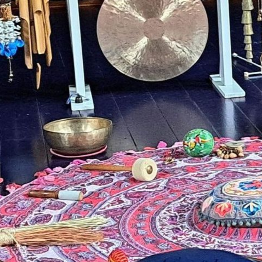 Vrouw ligt neer, ogen gesloten, gestreept shirt, muziekinstrumenten op de achtergrond, persoon in blauw.