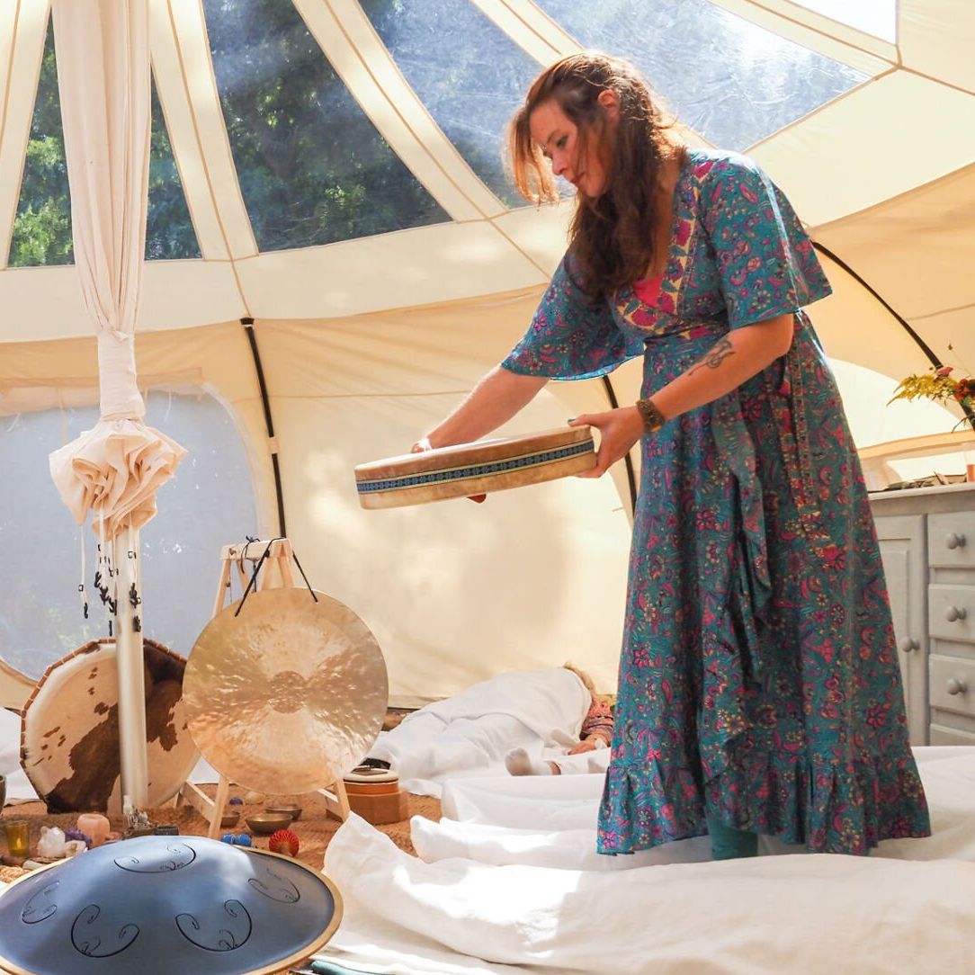 Vrouw in blauwe jurk die spullen in een tent ordent; muziekinstrumenten op de voorgrond.