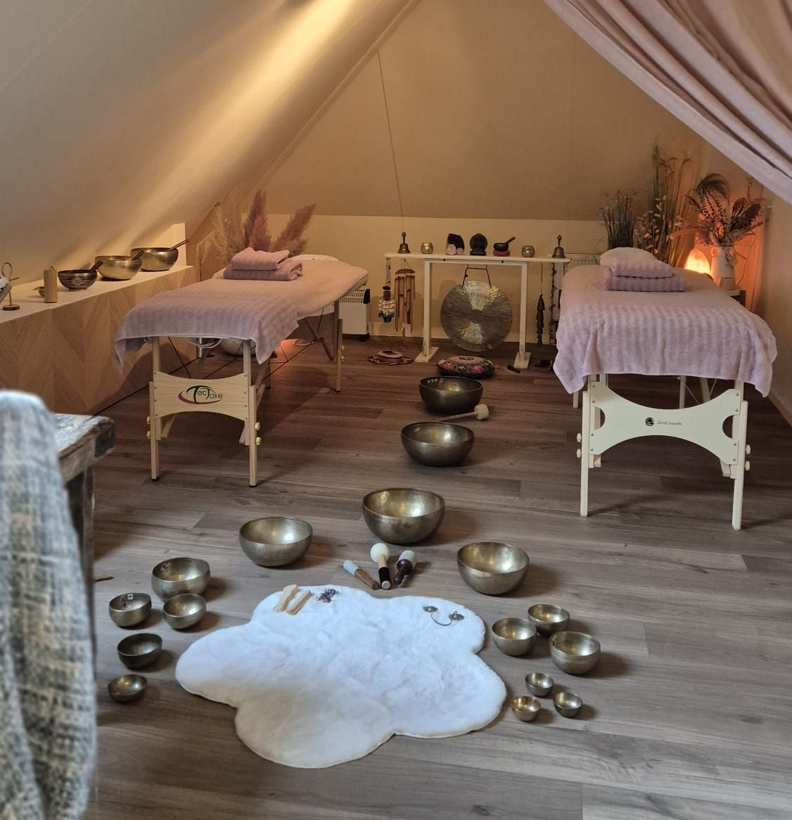 Spa-ruimte met massagetafels, klankschalen en een gong. Zachte verlichting en neutrale tinten.