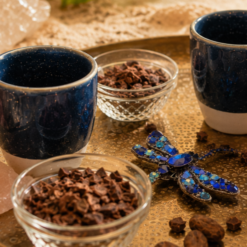 Een glas chocolademelk, cacaobonen, kristallen en een bosje salie op een houten ondergrond.