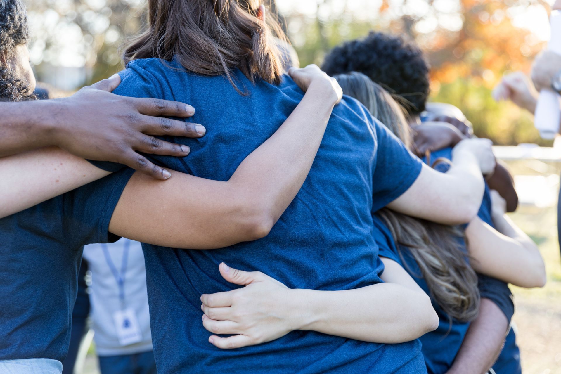 A group of volunteers hugging each other in a huddle after a work day. 