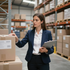 Warehouse worker in navy blazer checks boxes and holds a clipboard among stacked shelves