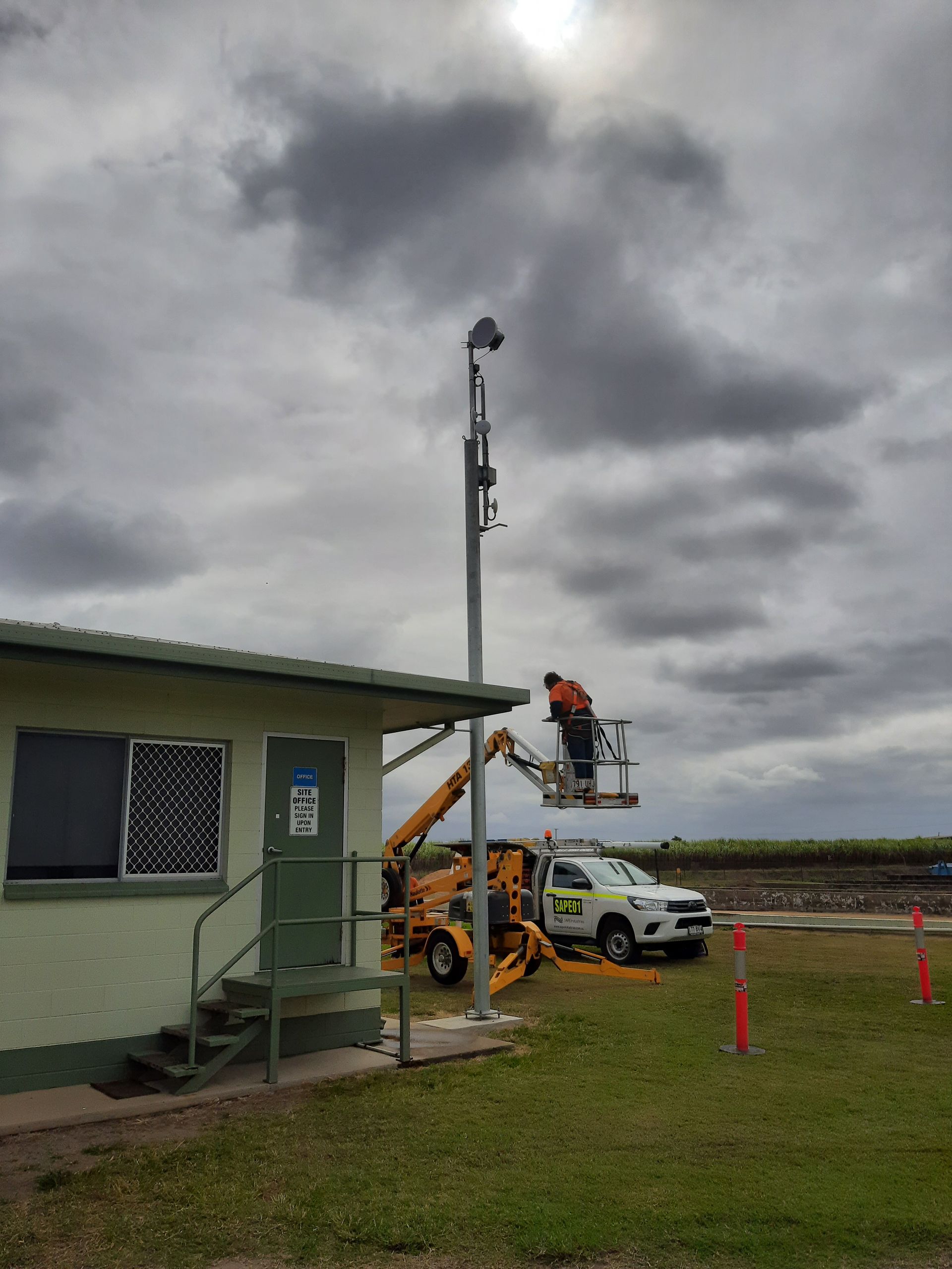 A man is working on a light pole in front of a building.