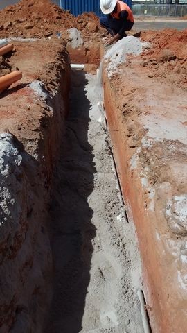 Construction Worker is Kneeling Down in a Trench in the Dirt — Sape Industries in Garbutt, QLD