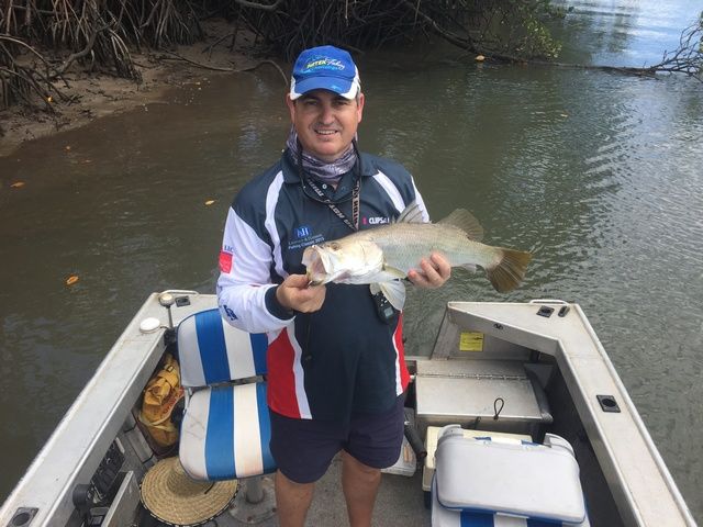 Man is Standing on a Boat Holding a Fish — Sape Industries in Garbutt, QLD