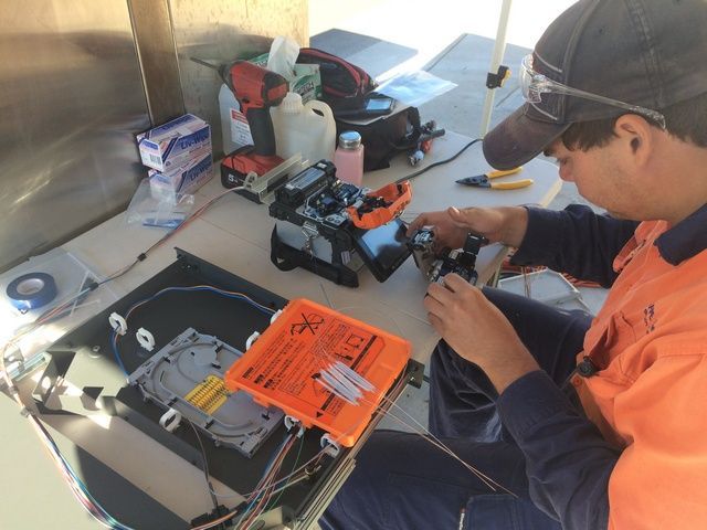 Skilled Person in an Orange Shirt is Working on a Machine — Sape Industries in Garbutt, QLD