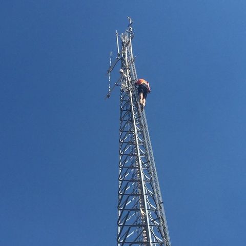 Man is Climbing a Very Tall Tower With a Blue Sky in the Background — Sape Industries in Garbutt, QLD