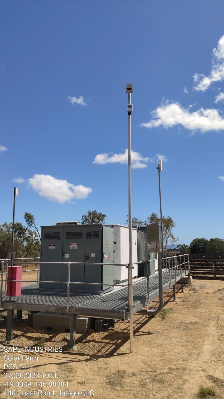 A large electrical box is sitting in the middle of a dirt field.