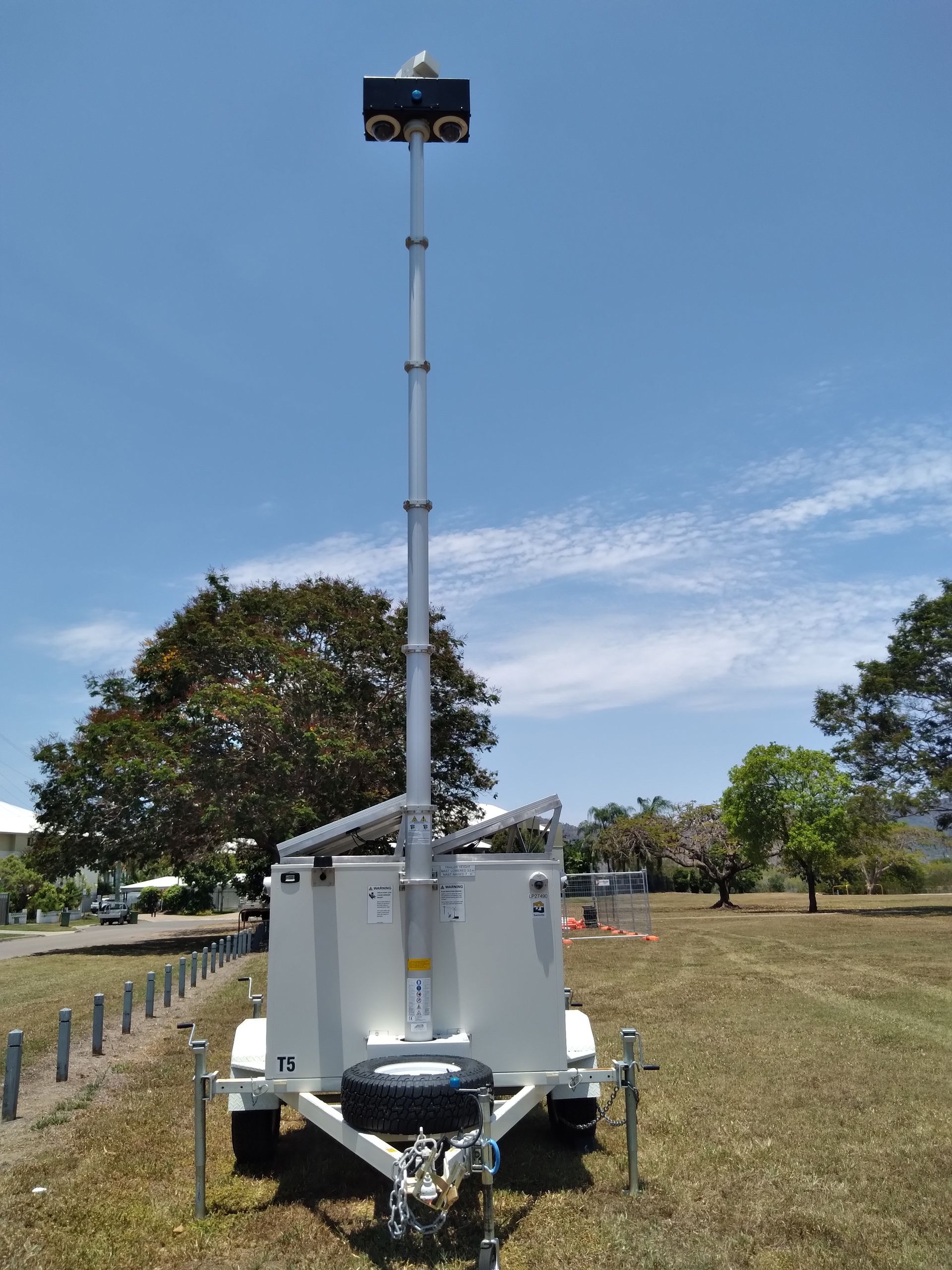 A trailer with a tower on top of it is parked in a grassy field.