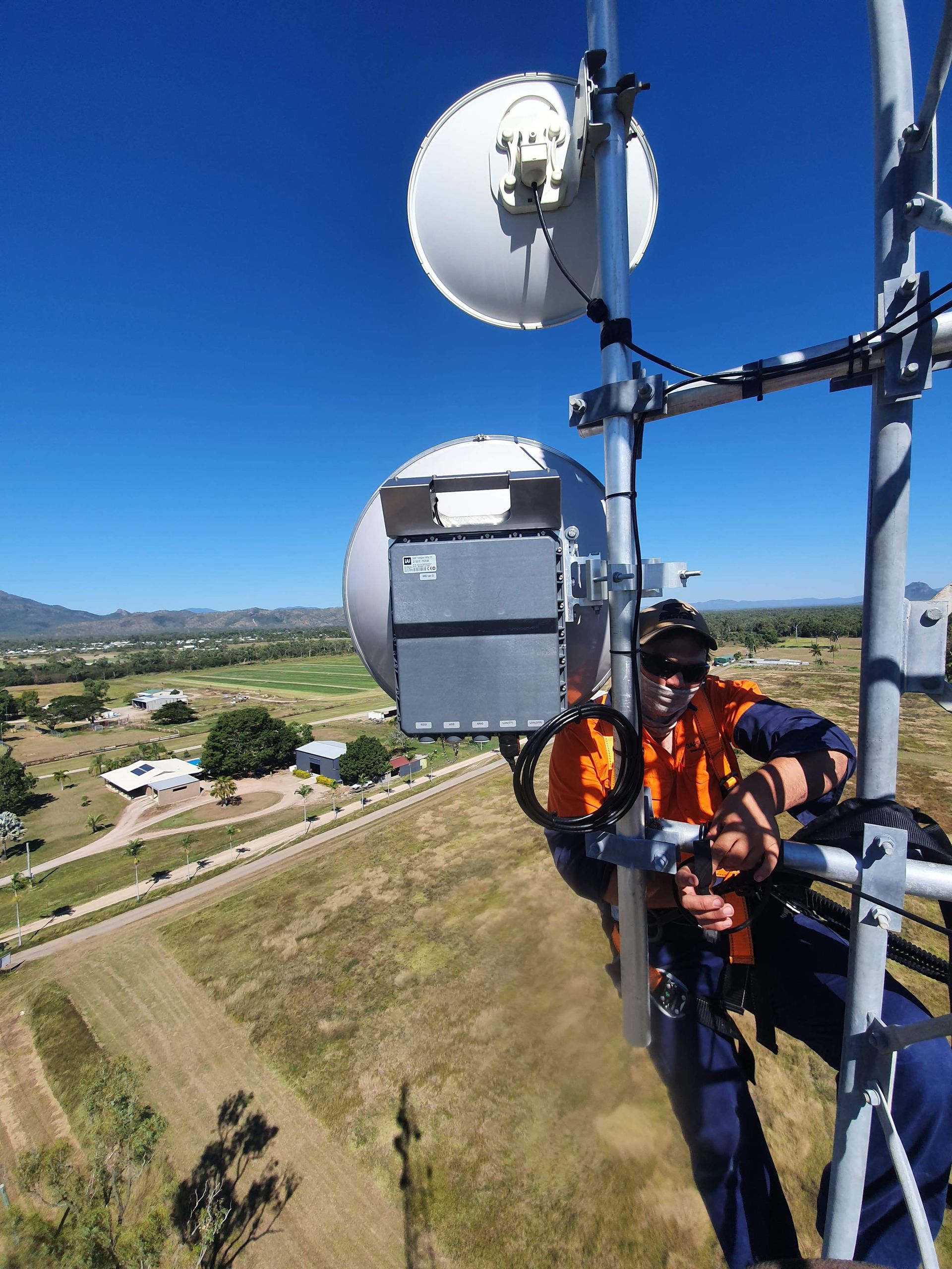 A man in an orange vest is working on a tower