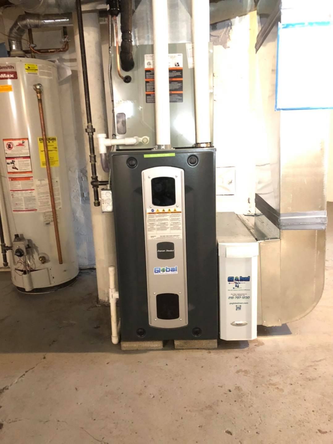 Furnace and humidifier unit in a basement setting. The furnace is black, next to a white humidifier and water heater.