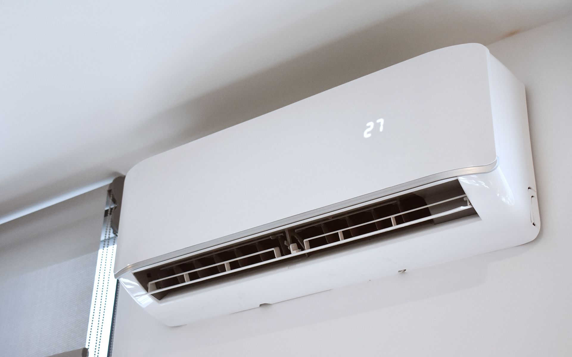 White wall-mounted air conditioner displaying a digital temperature readout.