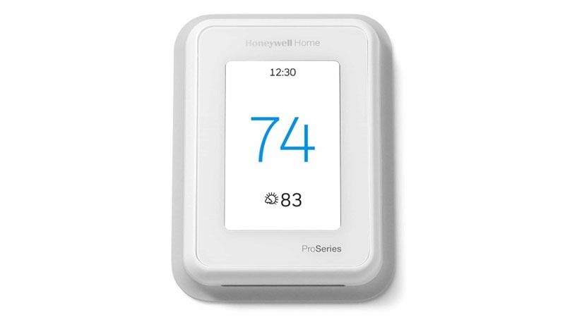 White Honeywell thermostat displaying 74 degrees with indoor temp 83 degrees.